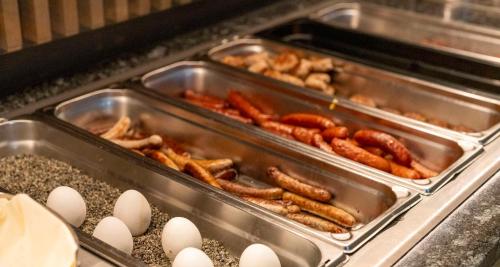 a bunch of hot dogs and eggs in trays at Sure Hotel by Best Western Hilden-Düsseldorf in Hilden