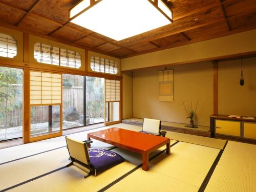 a living room with a table and chairs and windows at Kinjohro in Kanazawa