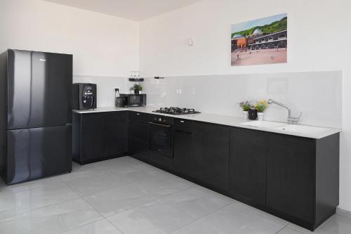 a kitchen with black cabinets and a black refrigerator at לוי-קיישן מגוון דירות גן ופנטהאוזים וסוויטות נוף ברחוב הצנחנים in Tiberias