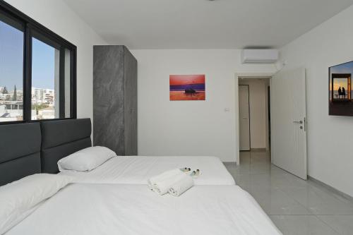 a bedroom with a white bed and a large window at לוי-קיישן מגוון דירות גן ופנטהאוזים וסוויטות נוף ברחוב הצנחנים in Tiberias
