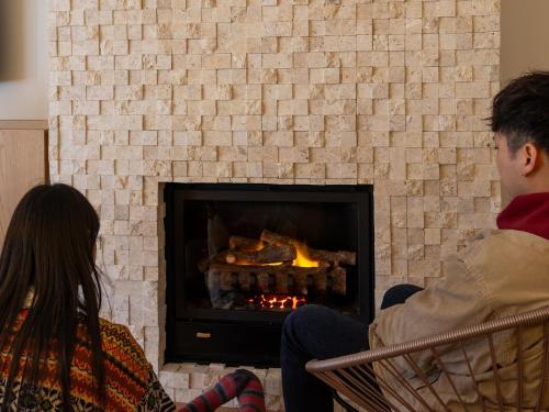 a man and a woman sitting in front of a fireplace at そらすな Beach Side Resort Hotel in Yukuhashi