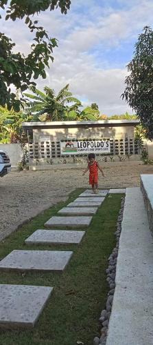 a person walking down a stone pathway in front of a building at Leopoldo's Kampsite and Sports Cafe in Cruz