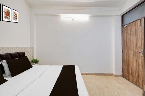 a bedroom with a bed and a wooden door at Super Hotel O GMS Road Near Bus Stand in Dehradun