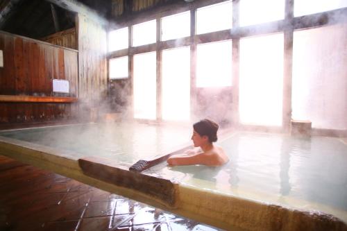 a woman bathing in a hot tub with steam at Awanoyu in Matsumoto