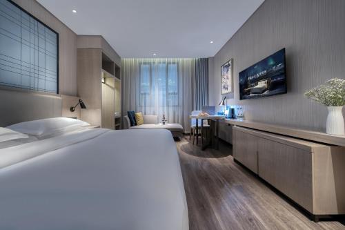 a hotel room with a bed and a desk at Echarm International Hotel Pazhou Convention and Exhibition Center Nanzhou Metro Station Branch - Free Shuttle Bus to Canton Fair Complex During Canton Fair Period in Guangzhou