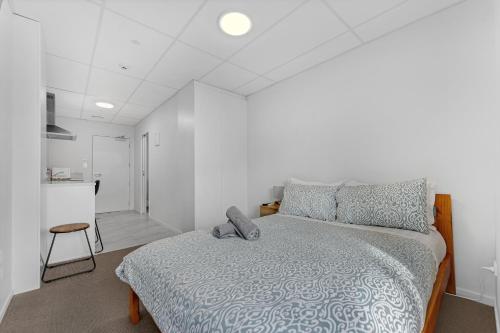 a bedroom with a bed and a bathroom with a kitchen at Onehunga Suites in Auckland