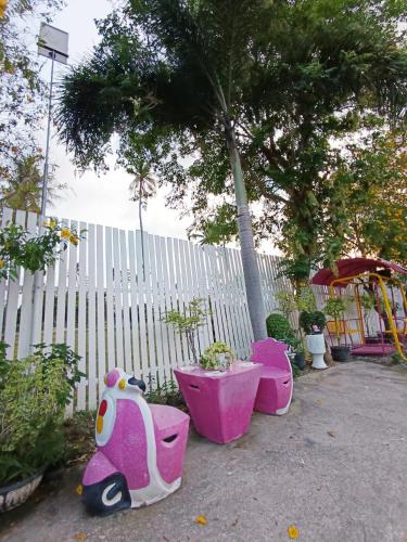 a pink and white scooteritures in front of a fence at Saan Rak Resort in Prachuap Khiri Khan
