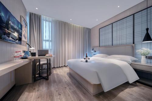 a bedroom with a large white bed and a desk at Echarm International Hotel Pazhou Convention and Exhibition Center Nanzhou Metro Station Branch - Free Shuttle Bus to Canton Fair Complex During Canton Fair Period in Guangzhou