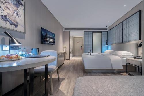a hotel room with a bed and a dining room at Echarm International Hotel Pazhou Convention and Exhibition Center Nanzhou Metro Station Branch - Free Shuttle Bus to Canton Fair Complex During Canton Fair Period in Guangzhou