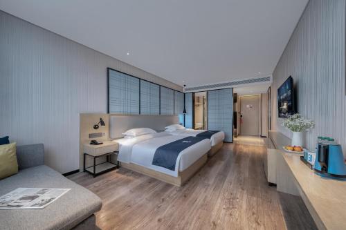 a bedroom with a large bed and a couch at Echarm International Hotel Pazhou Convention and Exhibition Center Nanzhou Metro Station Branch - Free Shuttle Bus to Canton Fair Complex During Canton Fair Period in Guangzhou