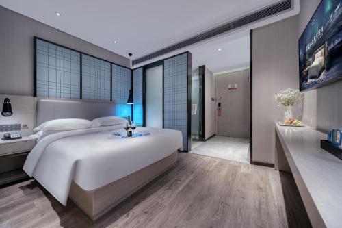 a bedroom with a large white bed and a bathroom at Echarm International Hotel Pazhou Convention and Exhibition Center Nanzhou Metro Station Branch - Free Shuttle Bus to Canton Fair Complex During Canton Fair Period in Guangzhou