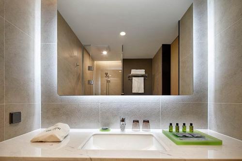 a bathroom with a sink and a large mirror at Staz Hotel Premier Dongtan in Hwaseong