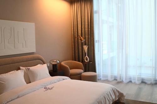 a bedroom with a bed and a chair and a window at Casa Royale Vacation Home - JVC in Dubai