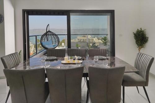 a dining room with a table and chairs and a large window at לוי-קיישן מגוון דירות גן ופנטהאוזים וסוויטות נוף ברחוב הצנחנים in Tiberias