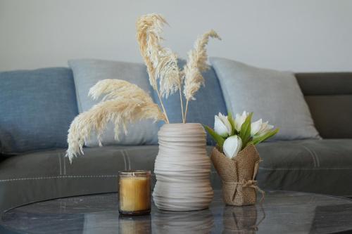 two vases on a table with flowers and a couch at לוי-קיישן מגוון דירות גן ופנטהאוזים וסוויטות נוף ברחוב הצנחנים in Tiberias