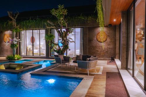 a pool in a room with furniture and plants at Villa Espresso Ubud in Sukawati