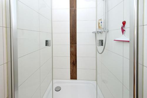 a bathroom with a shower with white tiles at Exkl App Seestern, W-LAN, 250 m zum Strand in Börgerende-Rethwisch