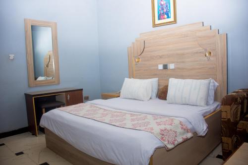 a bedroom with a bed with a wooden headboard and a mirror at Seagate Hospitality Empire in Okpuno Awka