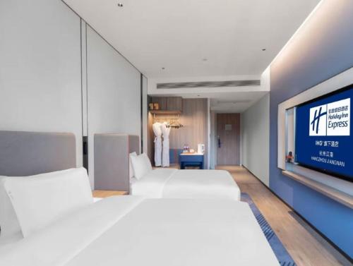 a room with four white beds and a tv at Holiday Inn Express Hangzhou Jiangnan by IHG in Hangzhou