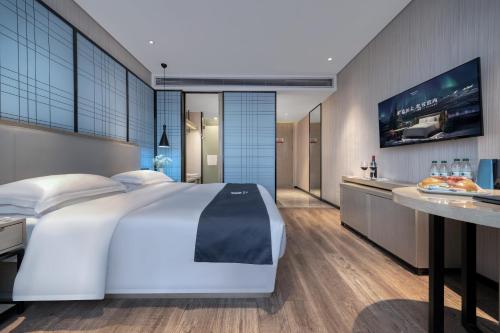 a bedroom with a large white bed and a tv at Echarm International Hotel Pazhou Convention and Exhibition Center Nanzhou Metro Station Branch - Free Shuttle Bus to Canton Fair Complex During Canton Fair Period in Guangzhou