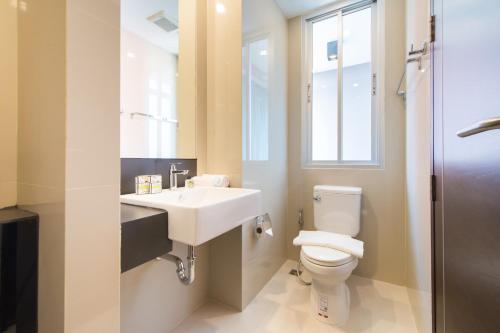 a bathroom with a toilet and a sink and a window at Zenniq in Bangkok