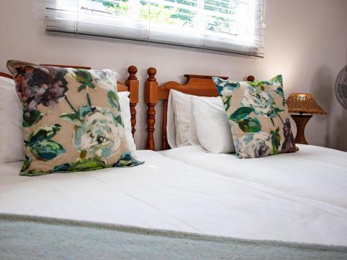 a bed with white sheets and pillows and a window at Tranquility Town Stays in Winterton