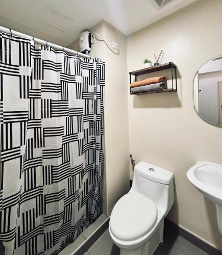 Un baño con inodoro y cortina de ducha. en Your Minimalist Cozy Haven, en Iloilo City