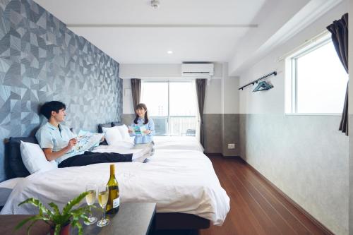duas pessoas sentadas em camas num quarto de hotel em Montana Wing Yebisu em Osaka