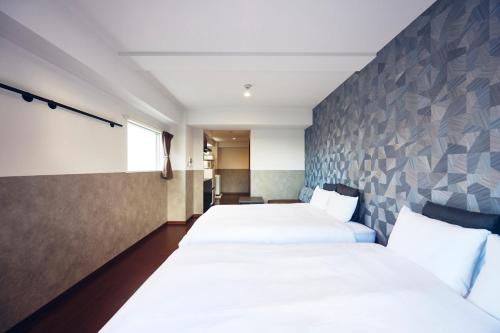 a hotel room with two beds and a wall at Montana Wing Yebisu in Osaka