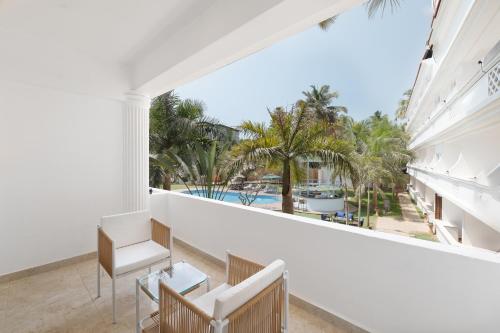 a balcony with a view of a pool and palm trees at White Wharf Beach Resort Morjim Goa in Morjim