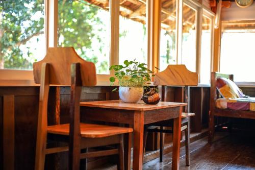 a table and chairs in a room with windows at Swasta Homestays Wayanad in Kaniyāmbetta
