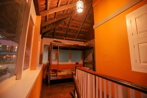 a room with orange walls and a staircase with a ladder at Swasta Homestays Wayanad in Kaniyāmbetta