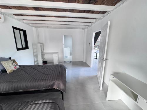 a white room with a bed and a hallway at Chiangmai Courtyard Residence บ้านสวนสวย บ้านถวาย in Bān Sawan