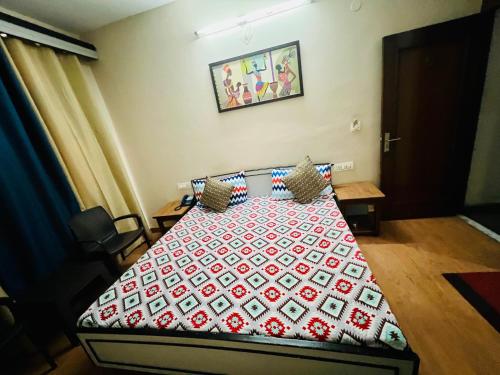 a bedroom with a bed with a red and white quilt at Hotel Shaan in Gangānagar