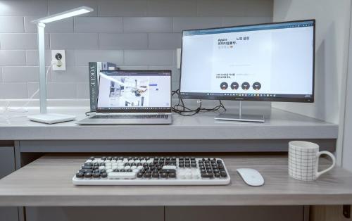 a desk with a computer and a laptop and a keyboard at Jeju Centerpoint N Hotel in Jeju