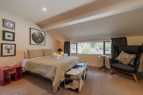a bedroom with a bed and a chair and a window at The Andromeda Hideaway - 6BR Hot tub BBQ in Lake Tekapo