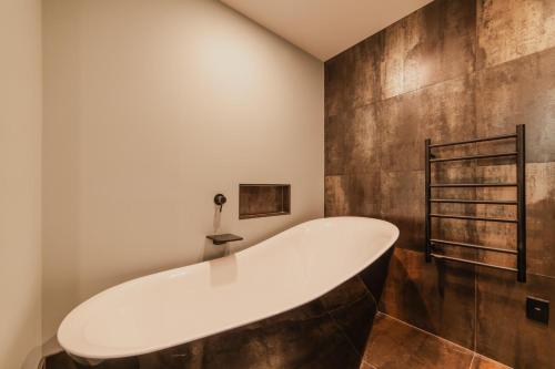 a bath tub in a bathroom with a wooden wall at The Andromeda Hideaway - 6BR Hot tub BBQ in Lake Tekapo