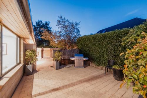 a patio with a table and a hedge at The Andromeda Hideaway - 6BR Hot tub BBQ in Lake Tekapo