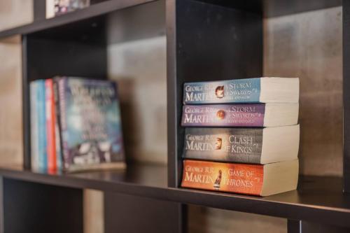 a stack of books sitting on a shelf at The Andromeda Hideaway - 6BR Hot tub BBQ in Lake Tekapo