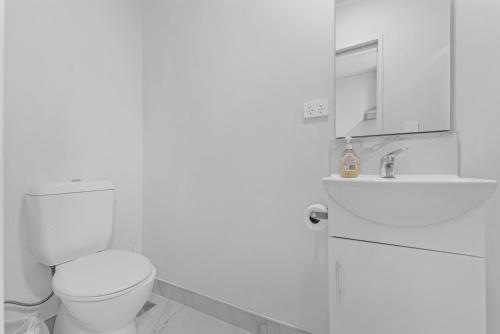 a white bathroom with a toilet and a sink at Onehunga Suites in Auckland