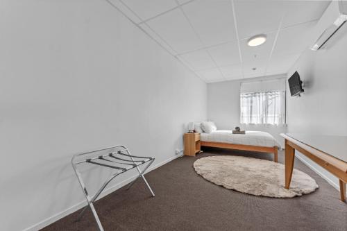 a white room with a bed and a television in it at Onehunga Suites in Auckland