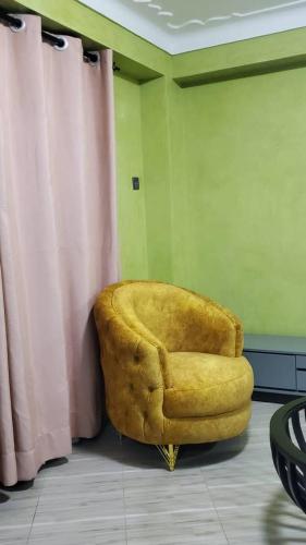 una silla amarilla sentada en la esquina de una habitación en Blaize Affaire Apartments, en Kampala
