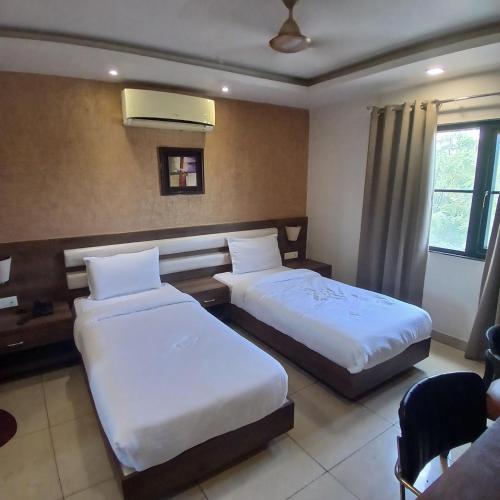 a hotel room with two beds and a window at Hotel Square 36 in Kota