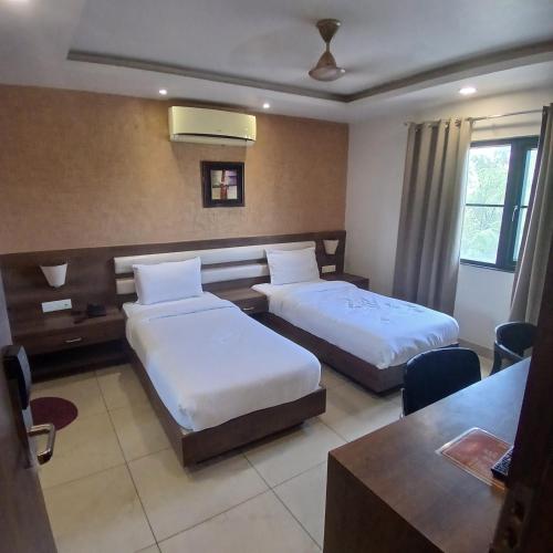 a hotel room with two beds and a table at Hotel Square 36 in Kota