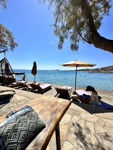 a wooden bench on a beach with chairs and umbrellas at 3BD Villa with breathtaking sea view in Azolimnos