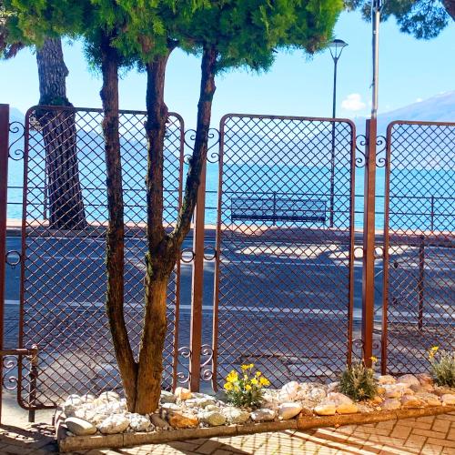 a fence with a tree in front of a street at Vista Lago - Lake Como collection in Domaso