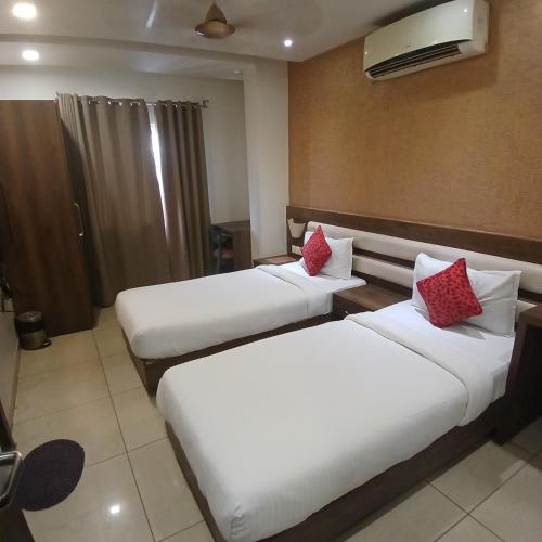 a hotel room with two beds with red pillows at Hotel Square 36 in Kota