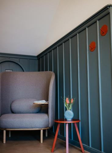 a chair and a table with a vase of flowers at Hotel Am Turm in Kaufbeuren