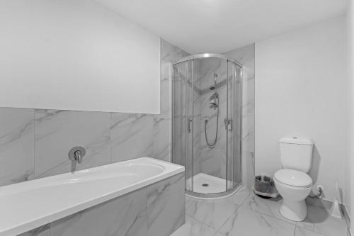 a white bathroom with a shower and a toilet at Onehunga Suites in Auckland