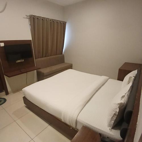a bedroom with a white bed and a television at Hotel Square 36 in Kota